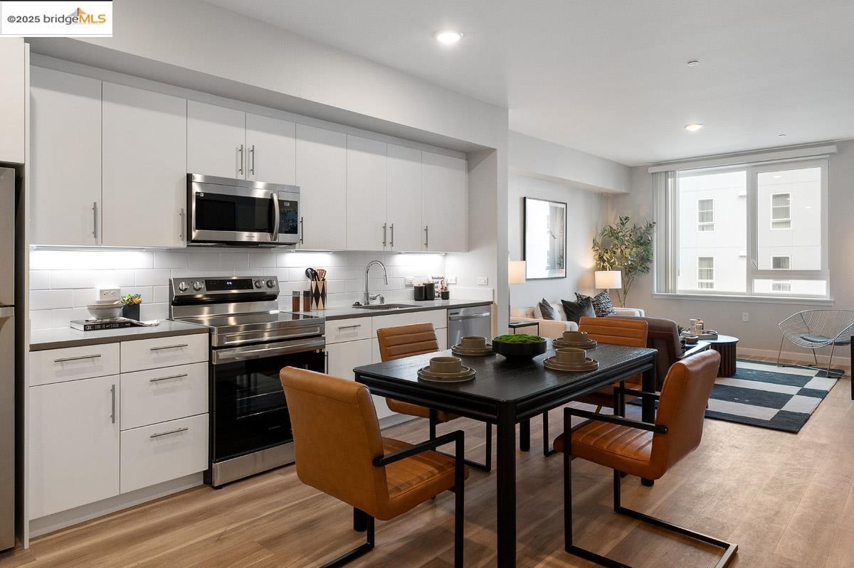 260 Brooklyn Basin Way, Unit 428 Oakland, CA 94606 - Photo 10 of 44 Kitchen featuring stainless steel appliances, white cabinets, tasteful backsplash, light wood-style floors, and recessed lighting