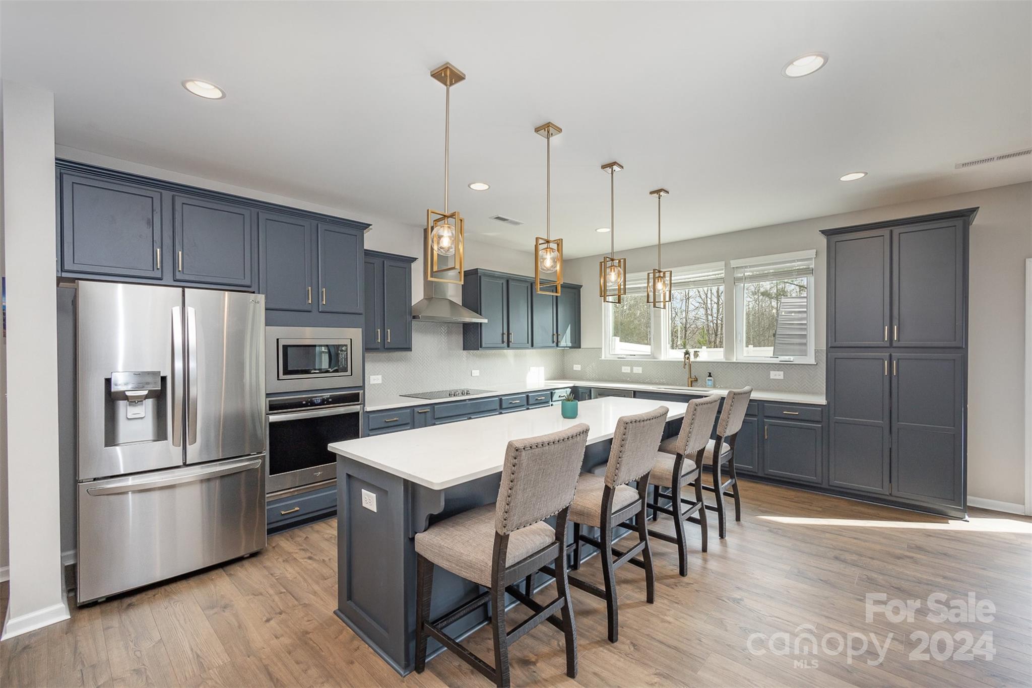 a kitchen with stainless steel appliances a dining table chairs a refrigerator and cabinets
