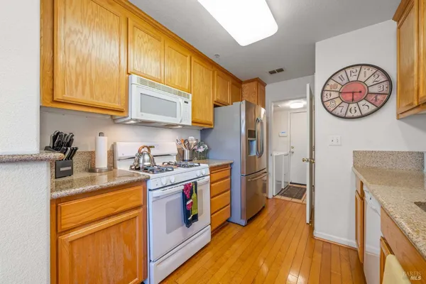 a kitchen with stainless steel appliances granite countertop a refrigerator a stove top oven and a sink