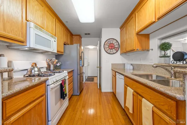 a kitchen with stainless steel appliances granite countertop a sink a stove and a wooden floors