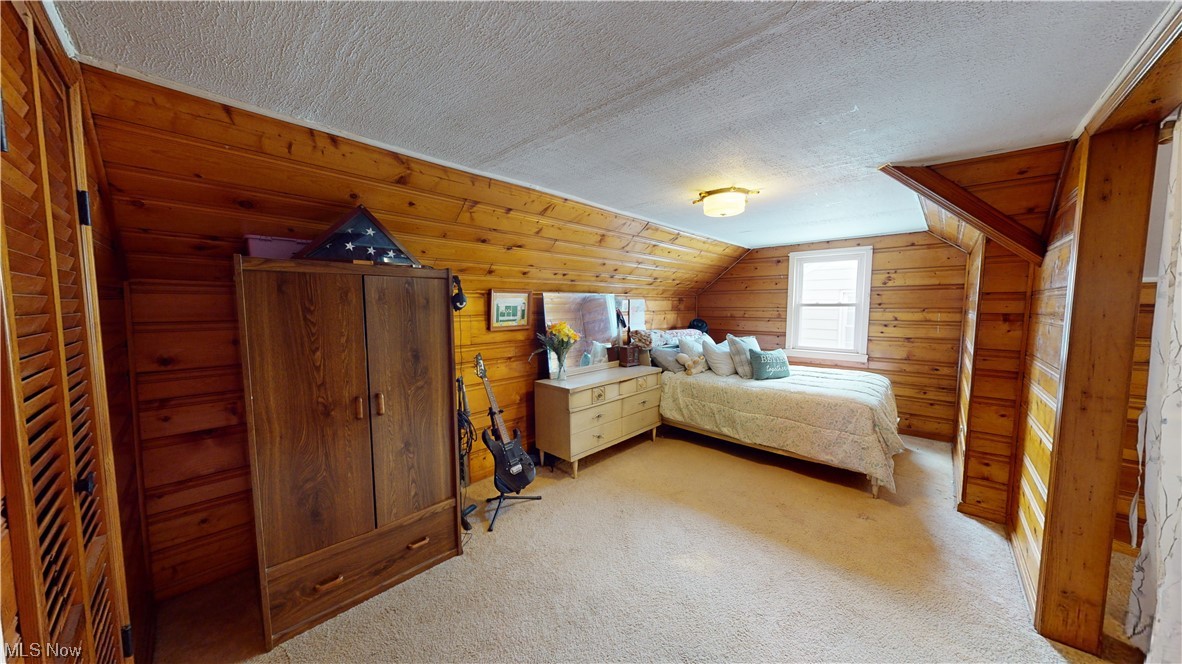 1331 Churchill Road Lyndhurst, OH 44124 - Photo 23 of 35 Bedroom with wood walls, light carpet, vaulted ceiling, and a textured ceiling