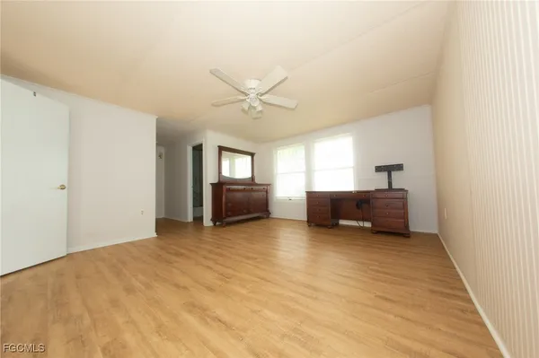 a view of an empty room with a window and a kitchen