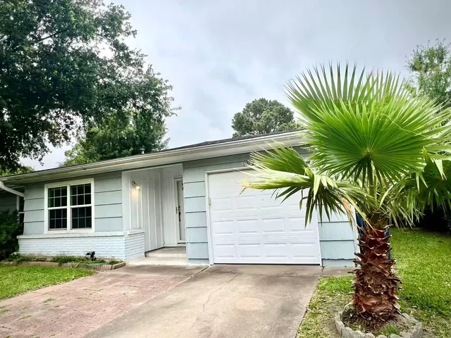 a front view of a house with a garden and a tree
