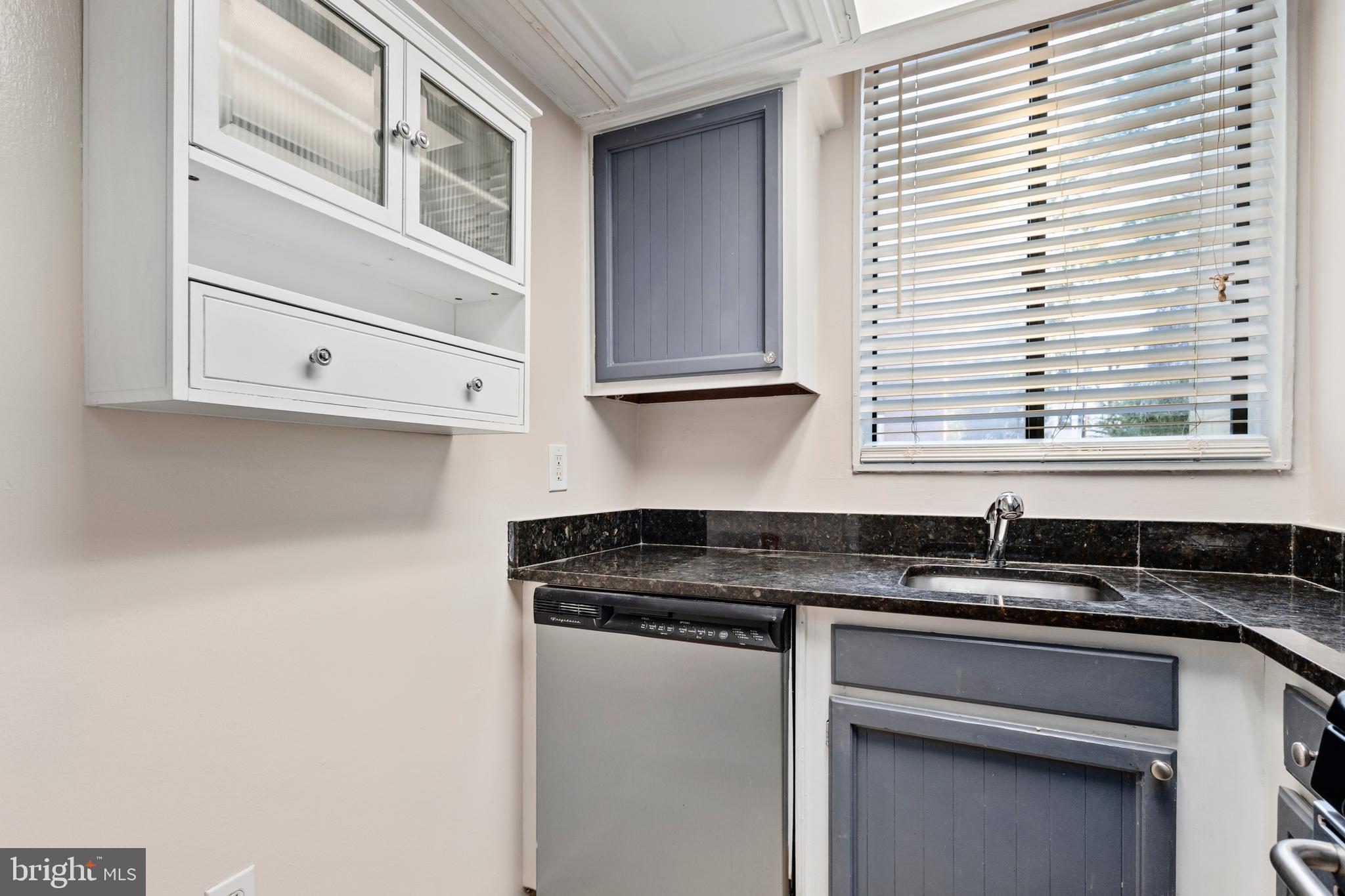 3825 Davis Place Northwest, Unit 103 Washington, DC 20007 - Photo 6 of 26 a kitchen with granite countertop white cabinets and black appliances