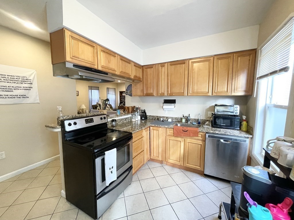 a kitchen with stainless steel appliances granite countertop a stove top oven a sink dishwasher and cabinets with wooden floor