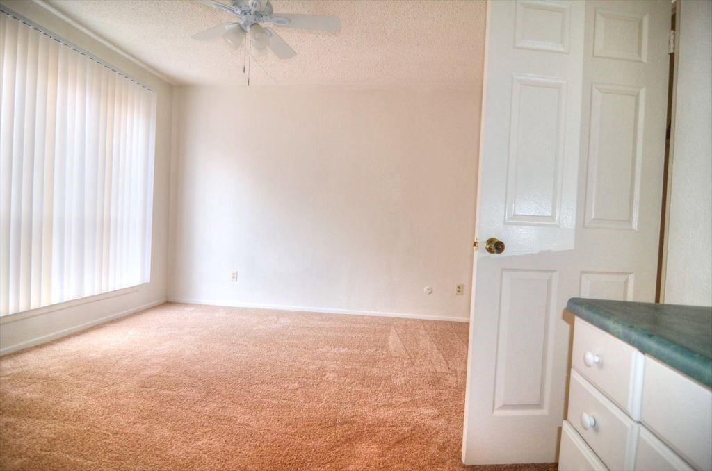 6503 Ridgecrest Road, Unit 110/J Dallas, TX 75231 - Photo 5 of 10 an empty room with a window and a ceiling fan