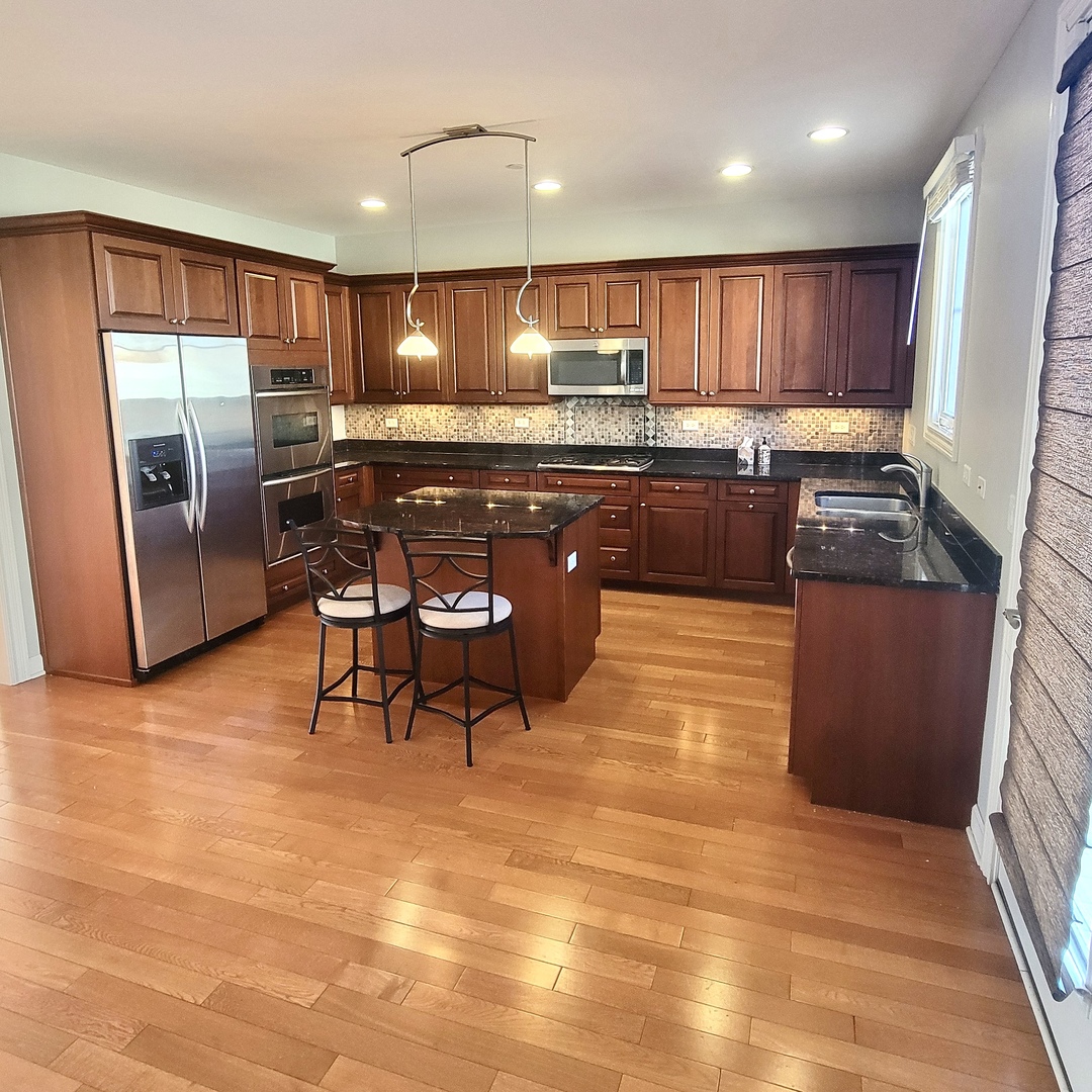 13 Busse Highway Park Ridge, IL 60068 - Photo 8 of 28 a kitchen with stainless steel appliances kitchen island granite countertop a table chairs in it and wooden floors