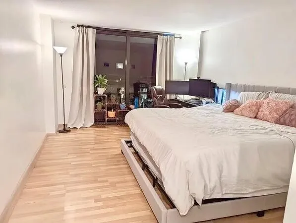 a spacious bedroom with a bed a mirror and lamp