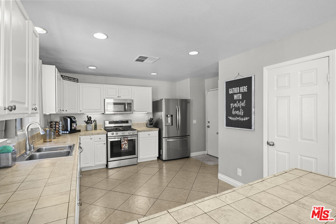 40335 Reata Road Palmdale, CA 93550 - Photo 12 of 37 a kitchen with stainless steel appliances granite countertop a refrigerator and a stove top oven