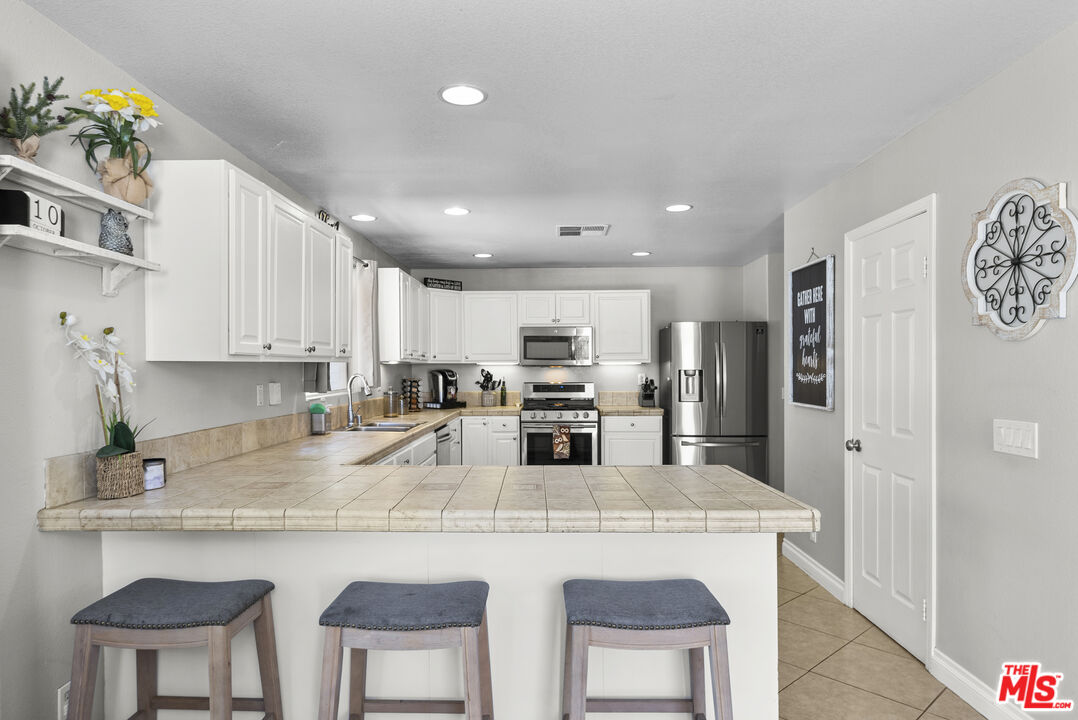40335 Reata Road Palmdale, CA 93550 - Photo 10 of 37 a kitchen with stainless steel appliances granite countertop a stove a refrigerator a sink a stove and white cabinets with wooden floor