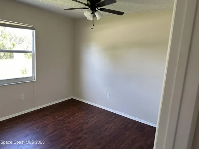 an empty room with a window and a fan