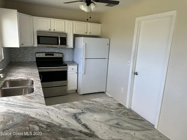 a kitchen with granite countertop a refrigerator and a stove top oven