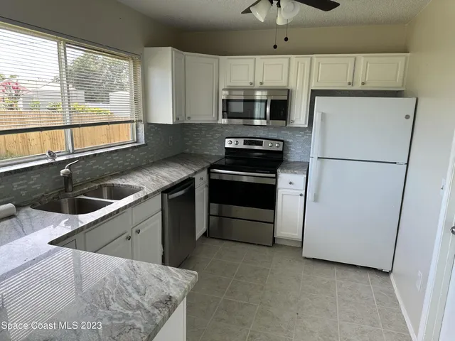 a kitchen with a sink a microwave a refrigerator and white cabinets