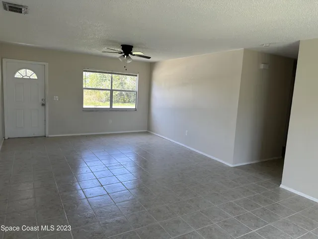 an empty room with windows and a ceiling fan