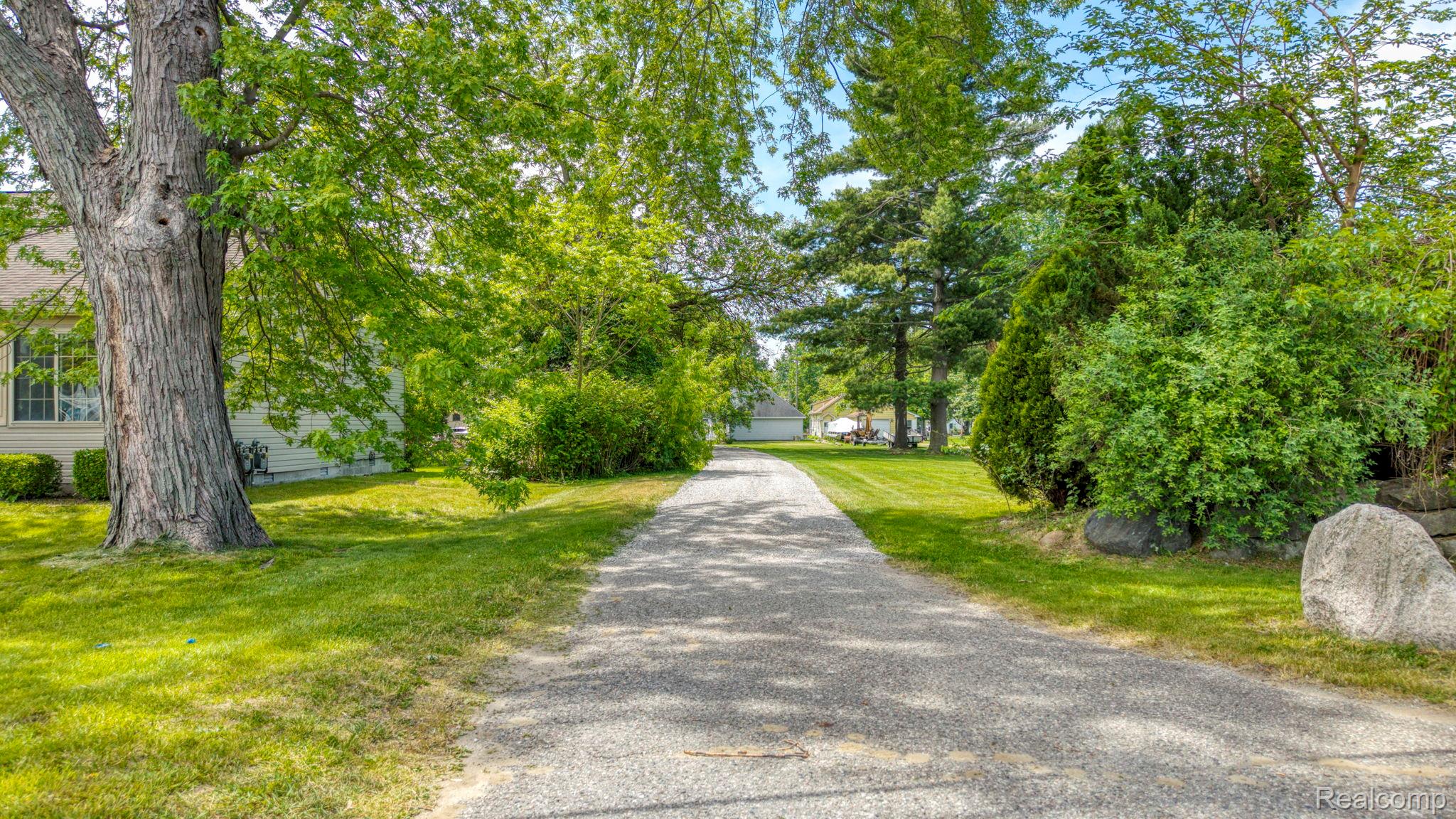 401 Pointe Tremble Road Algonac, MI 48001 - Photo 4 of 40 Long gravel driveway framed by mature trees and lush green landscaping