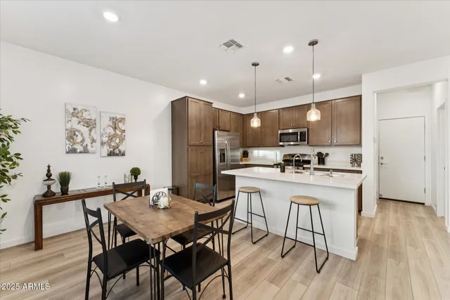 a kitchen with a dining table chairs refrigerator and microwave