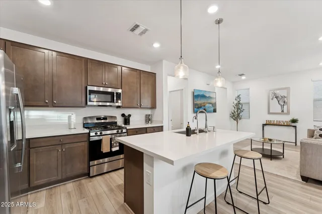 a kitchen with stainless steel appliances kitchen island granite countertop a sink a stove a refrigerator cabinets and chairs