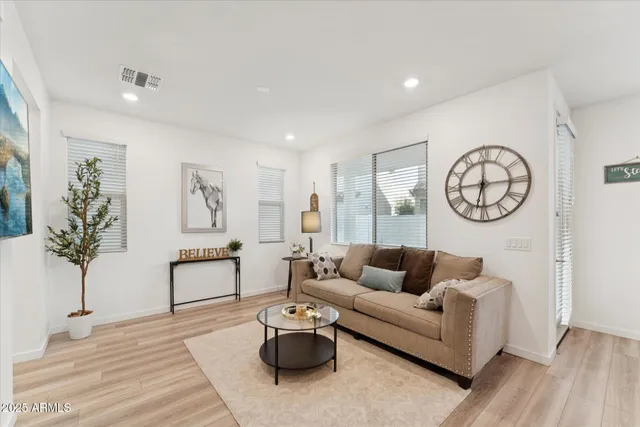 a living room with furniture a clock on wall and a window