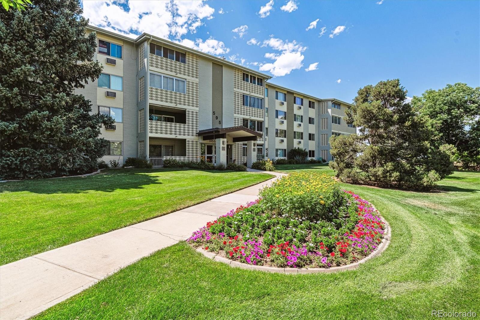 595 South Alton Way, Unit 7B Denver, CO 80247 - Photo 22 of 38 a view of a white house with a big yard and potted plants