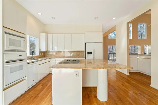 a kitchen with stainless steel appliances granite countertop a refrigerator a stove and white cabinets with wooden floor