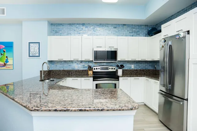 a kitchen with kitchen island granite countertop a refrigerator oven a sink and dishwasher