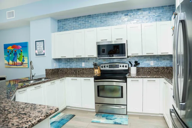 a kitchen with stainless steel appliances granite countertop a stove a sink and a microwave