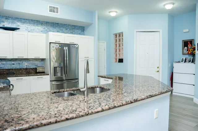 a kitchen with stainless steel appliances granite countertop a sink and a refrigerator