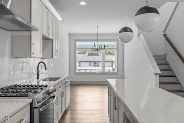 a kitchen with granite countertop a stove a sink a dining table and chairs