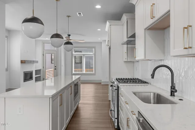 a kitchen with stainless steel appliances granite countertop a sink a stove and a wooden floors