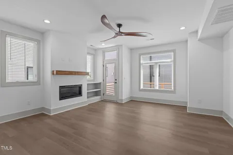 a view of an empty room with wooden floor fireplace and a window