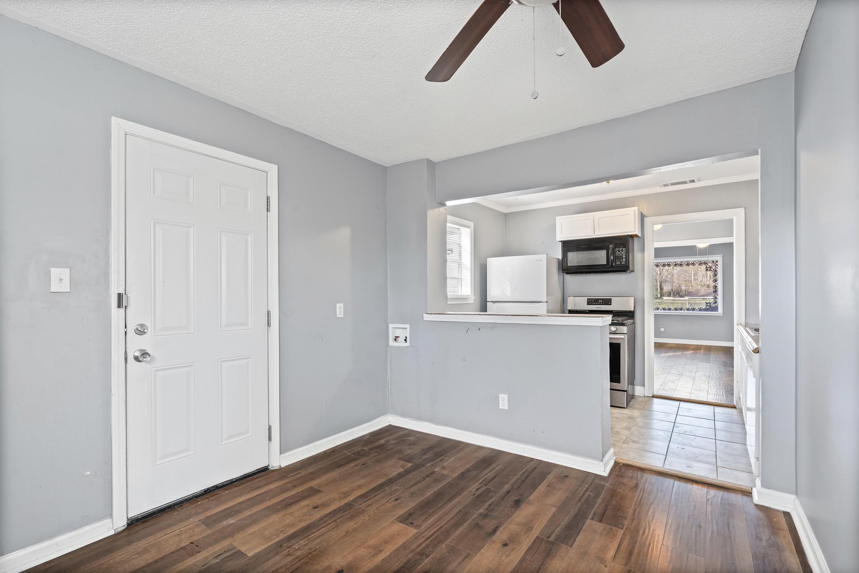 1848 Wynton Street Memphis, TN 38106 - Photo 12 of 22 Unfurnished living room featuring dark wood-type flooring, a ceiling fan, a textured ceiling, and plenty of natural light