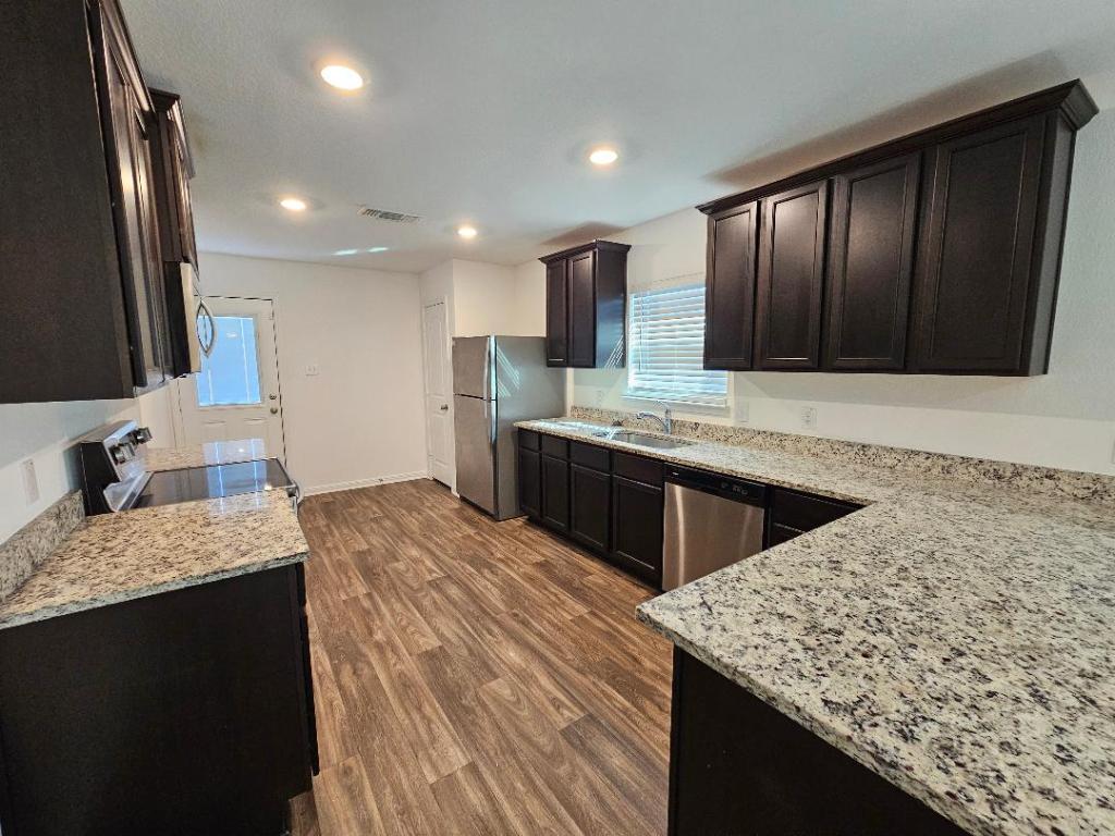 17904 Speculator Lane Elgin, TX 78621 - Photo 4 of 15 Kitchen with granite countertops, dark brown cabinets, appliances with stainless steel finishes, recessed lighting, and dark wood finished floors