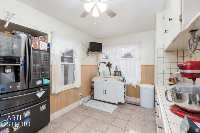 875 Patterson Street Ogden, UT 84403 - Photo 5 of 38 Kitchen featuring stainless steel refrigerator with ice dispenser, white cabinetry, wainscoting, a ceiling fan, and tile countertops