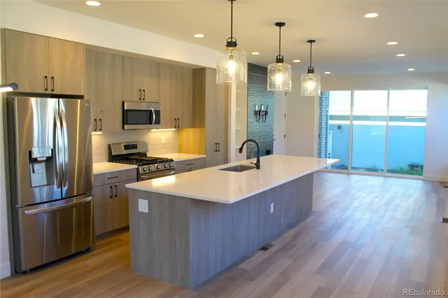 a kitchen with kitchen island a sink appliances a counter space and a window