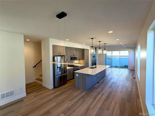 a living room with hard wood floors and a kitchen
