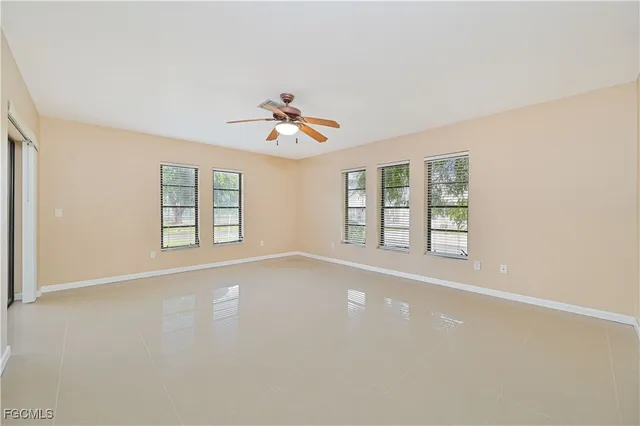 an empty room with windows and ceiling fan