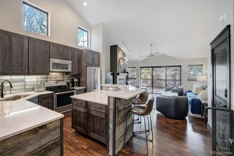 a kitchen with stainless steel appliances granite countertop a stove a refrigerator a sink a dining table and chairs with wooden floor