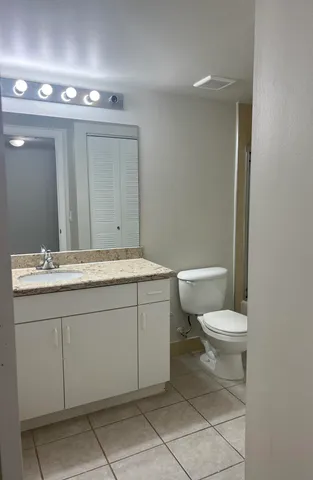 a bathroom with a granite countertop sink mirror vanity and toilet