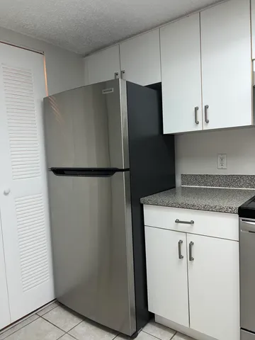 a close view of a refrigerator in kitchen and stainless steel appliances wooden cabinets