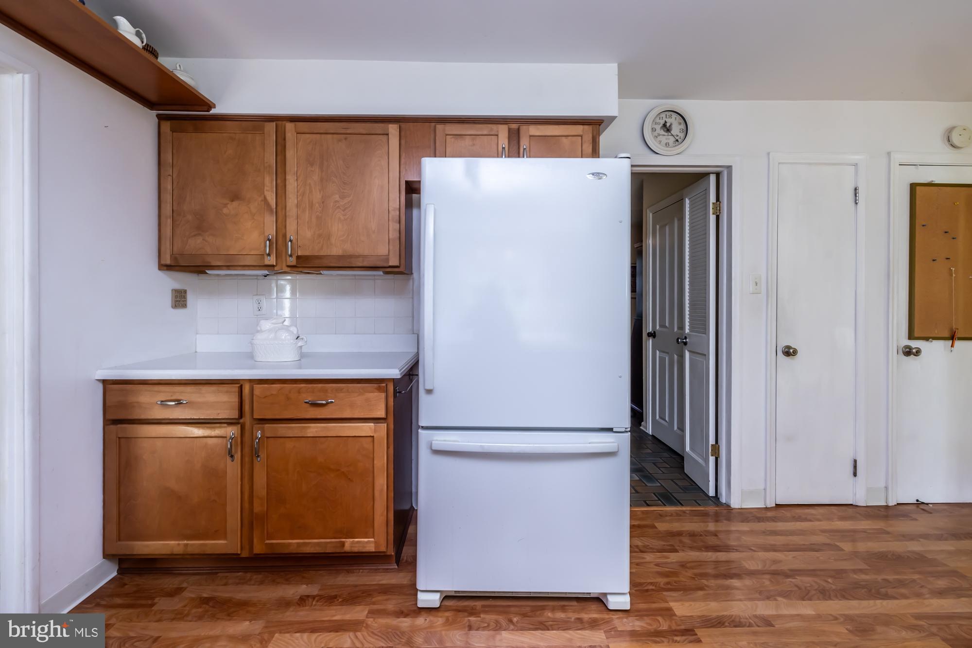 12 Flintshire Road Malvern, PA 19355 - Photo 22 of 50 a view of a refrigerator in kitchen and an empty room with wooden floor
