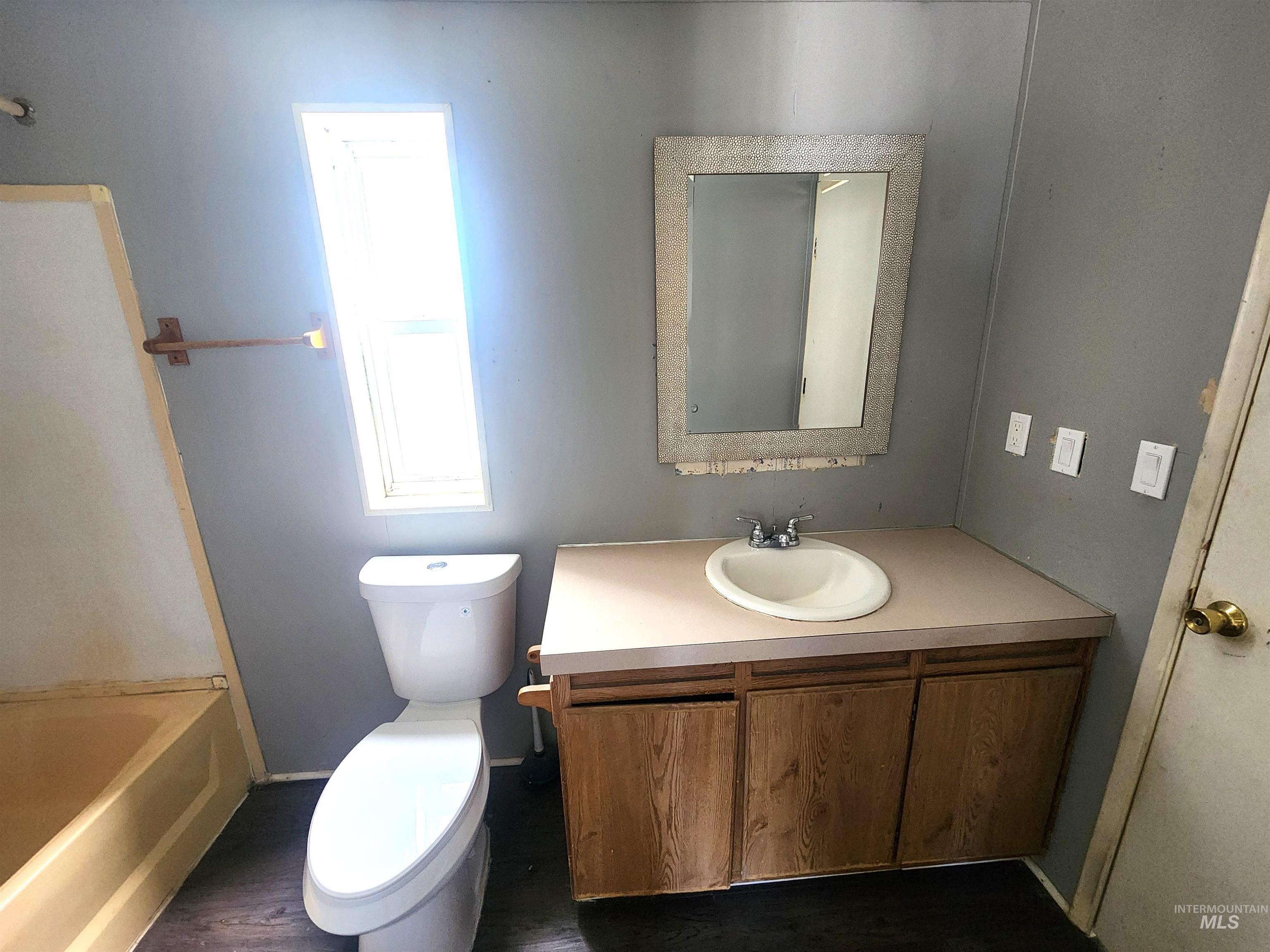 616 North Kings Road Nampa, ID 83687 - Photo 5 of 12 Bathroom featuring a vanity with an integrated sink, a framed mirror, a window for natural light, and dark-finish flooring