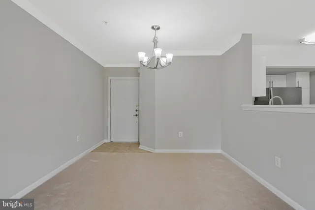 a view of an empty room with a chandelier fan