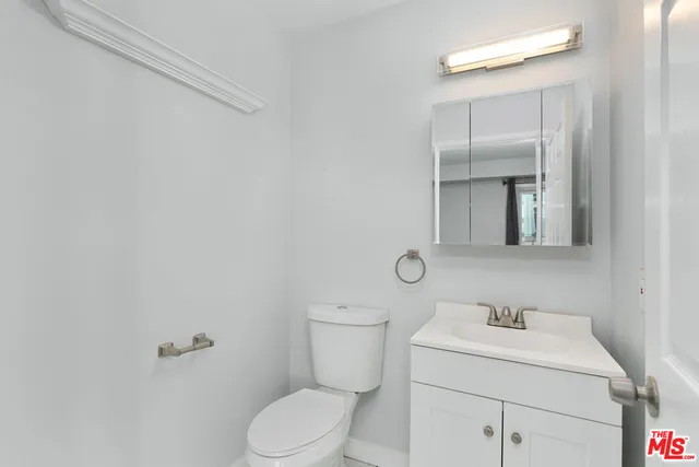 a bathroom with a toilet sink vanity and mirror
