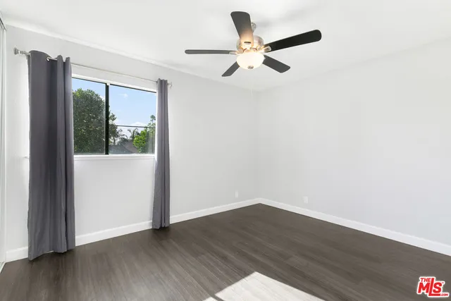 an empty room with wooden floor fan and windows