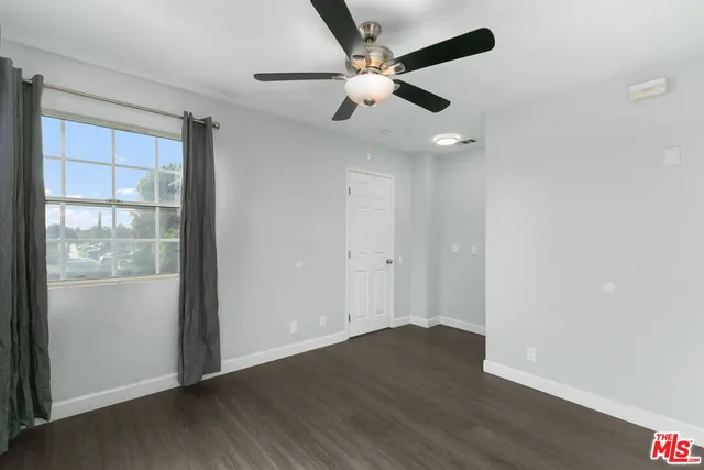 an empty room with wooden floor fan and windows