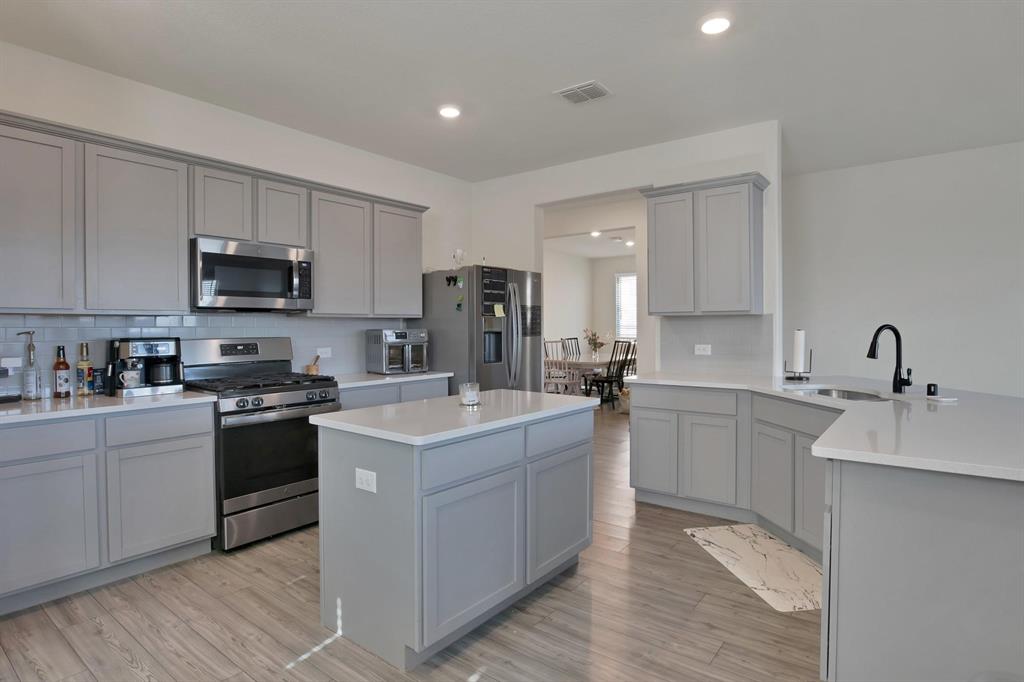 621 Ridgeback Trail Fort Worth, TX 76052 - Photo 6 of 22 Kitchen featuring light gray cabinetry, white countertops, stainless steel appliances, a center island, and wood-finish flooring