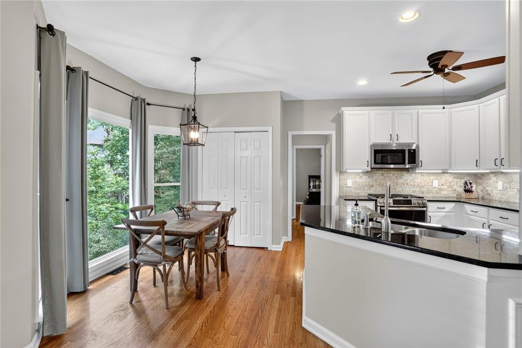 4760 Fontwell Court Suwanee, GA 30024 - Photo 6 of 43 a kitchen with stainless steel appliances granite countertop a stove a refrigerator a microwave a dining table and chairs with wooden floor