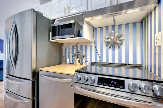 a kitchen with stainless steel appliances granite countertop a refrigerator a stove and a sink with wooden floor