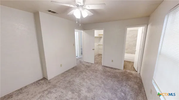 an empty room with a bathroom and a chandelier fan