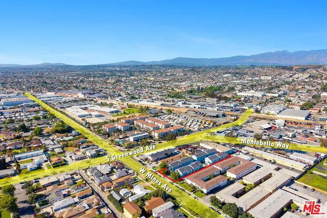 an aerial view of a city with lots of residential buildings and mountain view in back